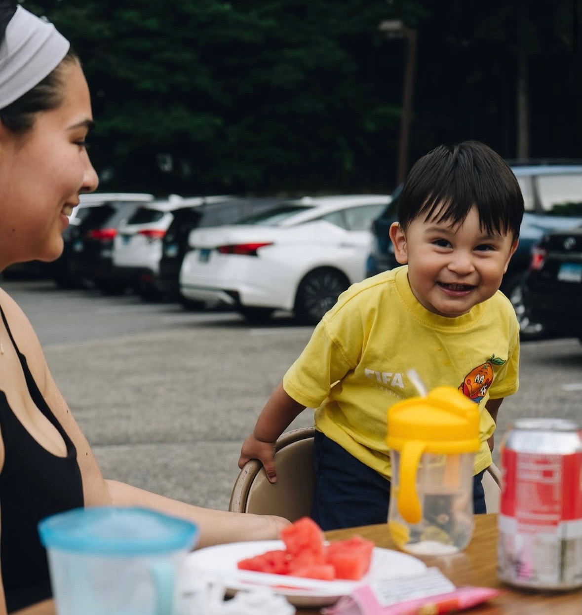 Toddler laughing at a picnic table with fresh watermelon