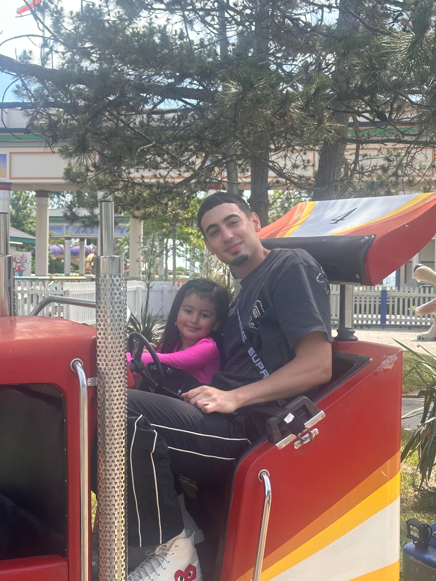 Dad and daughter smiling together on a red truck ride at the amusement park